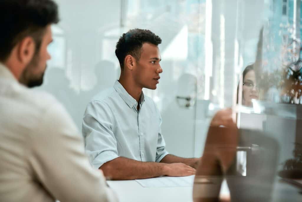 At the meeting. Young african man discussing something with his colleagues while sitting at the