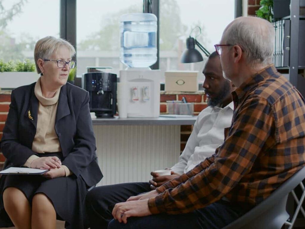 Woman psychiatrist giving advice to multi ethnic people with addiction at aa therapy session