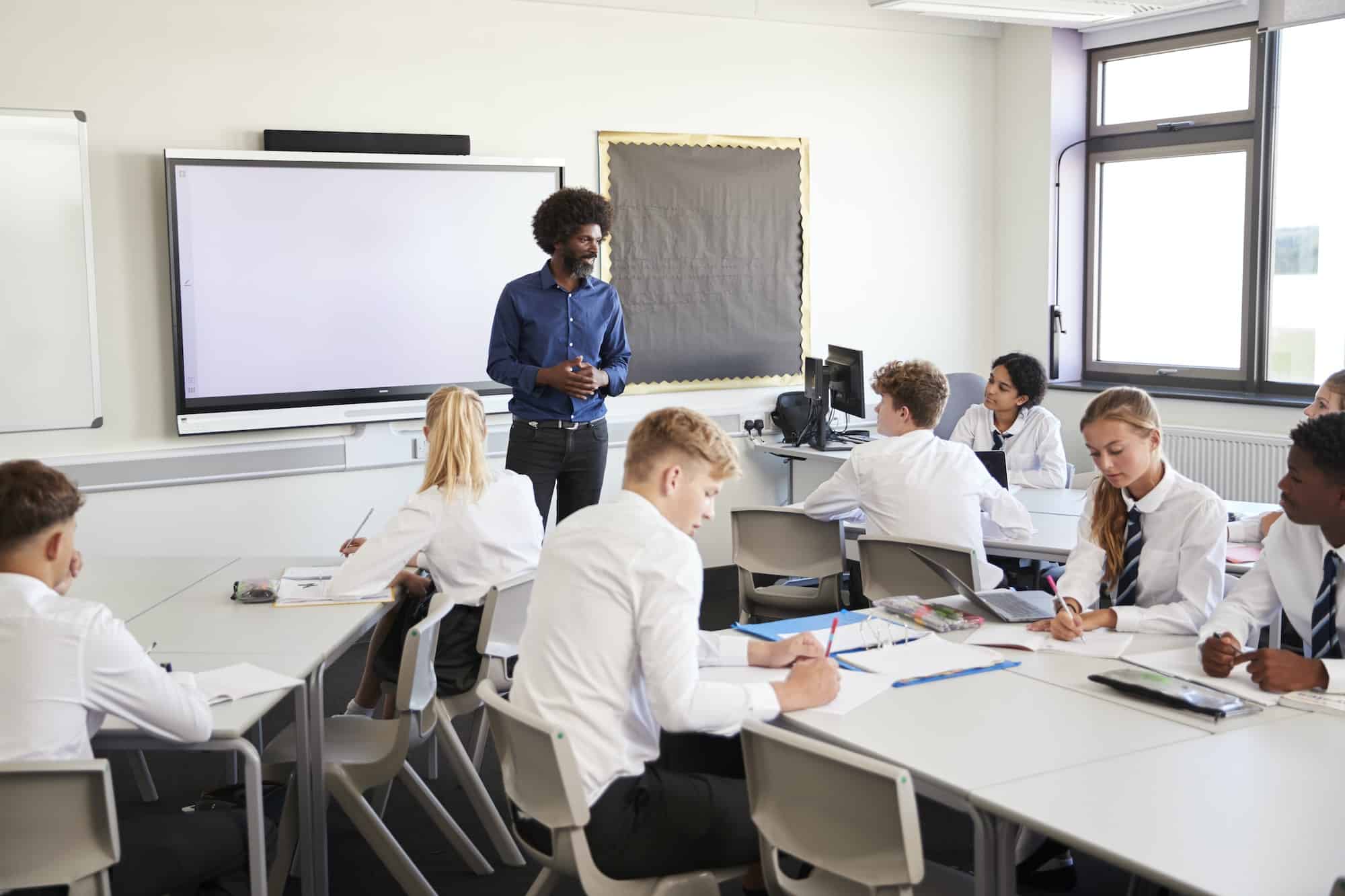 Teacher standing next to an interactive whiteboard in a classroom